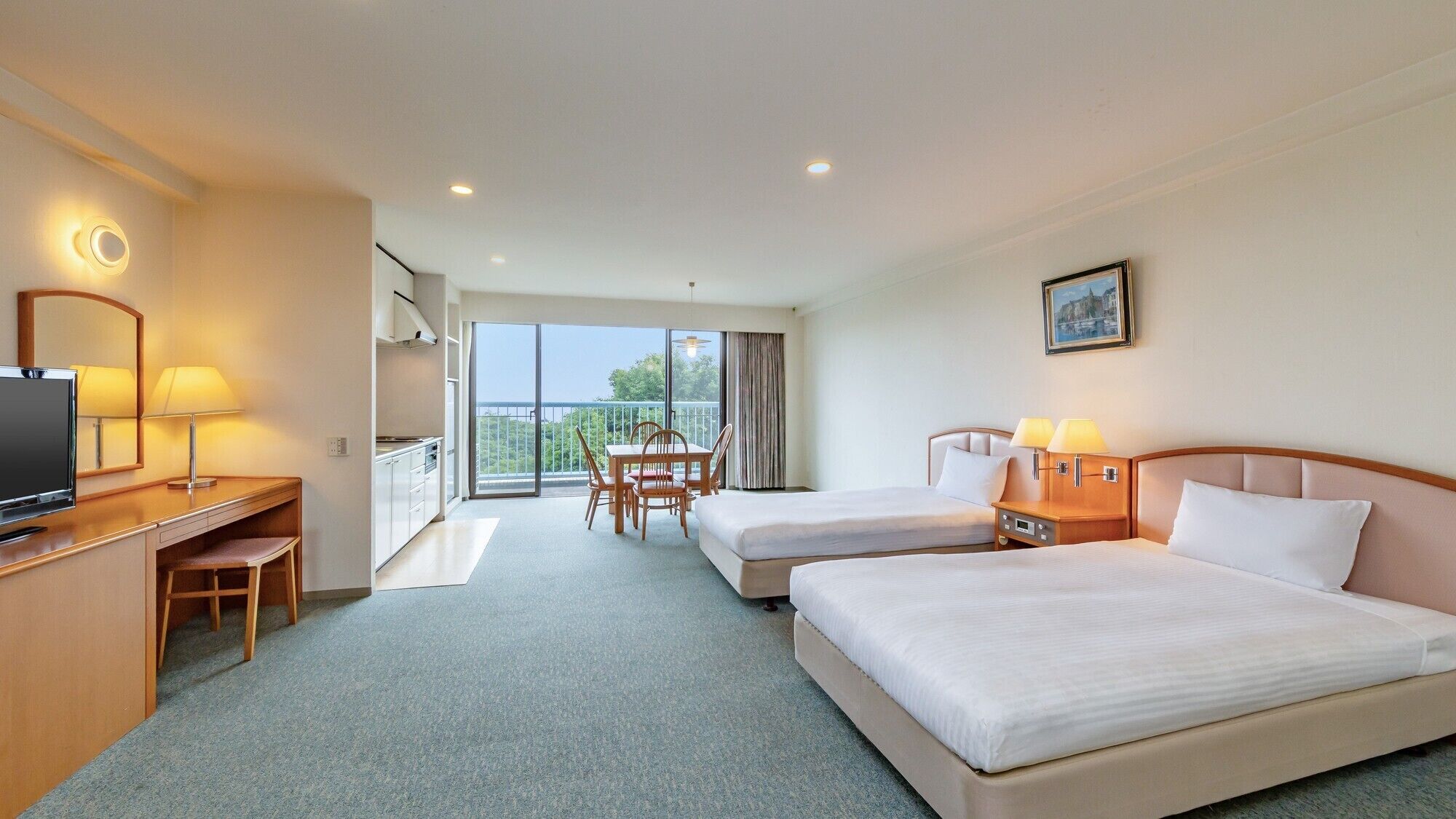 A hotel room with two beds, a desk with a TV, a balcony with a table and chairs, and a painting on the wall.
