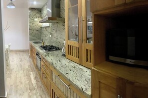 Eine Küche mit Gaskochfeld, Holzschränken und einem eingebauten Backofen.