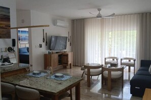 Ein Wohnzimmer mit Essbereich, Fernseher und Deckenventilator.
