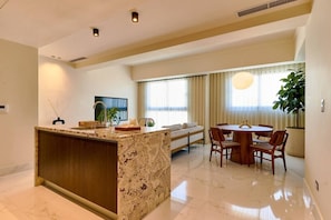 A modern kitchen with a marble island, a dining area with a round table and chairs, and a large window with curtains. - ® LUX {Arpel} Experience @DowntownSD +Pool+Gym (Santo Domingo)