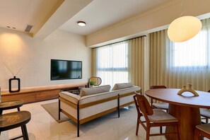 A modern living room with a sofa, a TV, a dining table, and a chandelier. - ® LUX {Arpel} Experience @DowntownSD +Pool+Gym (Santo Domingo)