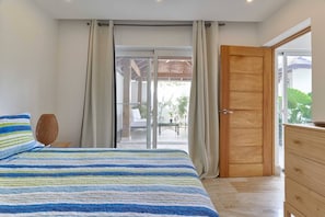A bedroom with a bed, a wooden dresser, a window with curtains, and a view of the outdoors. - ®{Monserrat Beach Condo} @Terrenas +Pool+Wifi+BBQ (Las Terrenas)