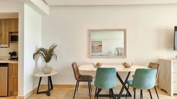 A modern dining area with a white table, teal chairs, and a decorative plant.
