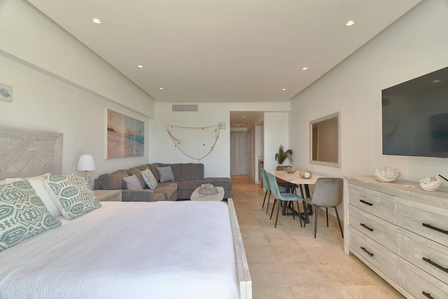 Um quarto com cama, sofá, escrivaninha e televisão.