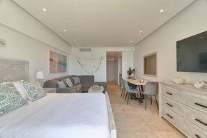 Um quarto com cama, sofá, escrivaninha e televisão.