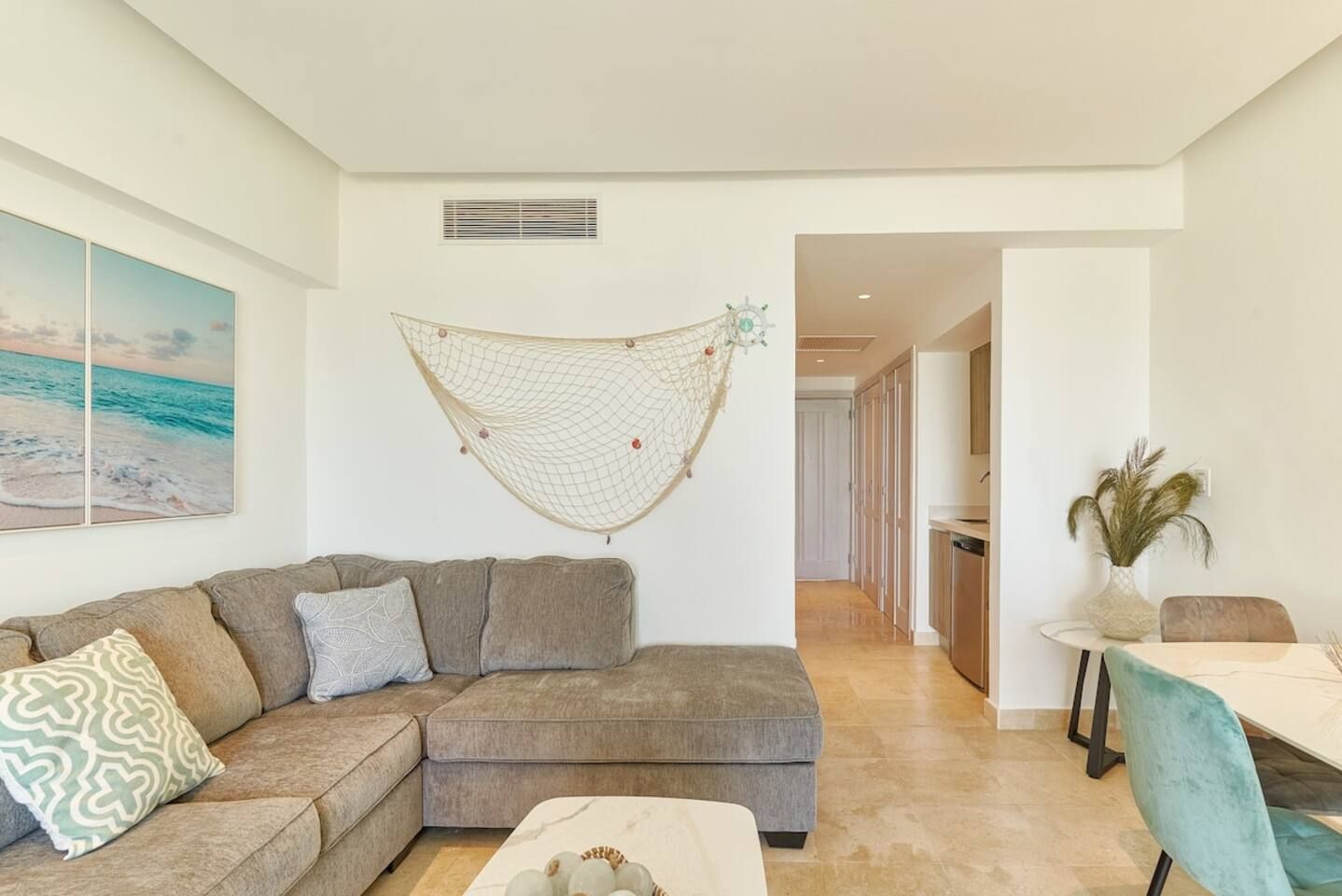 A modern living room with a sectional sofa, a coffee table, and a hammock. There is a dining area with a table and chairs.