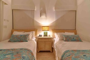 Ein Hotelzimmer mit zwei Betten, einem Nachttisch mit Lampe und einem kleinen Beistelltisch.