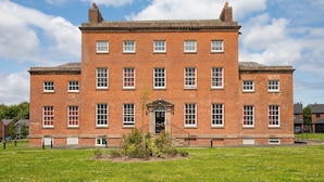 A large brick building with a symmetrical facade, multiple windows, and a central entrance.