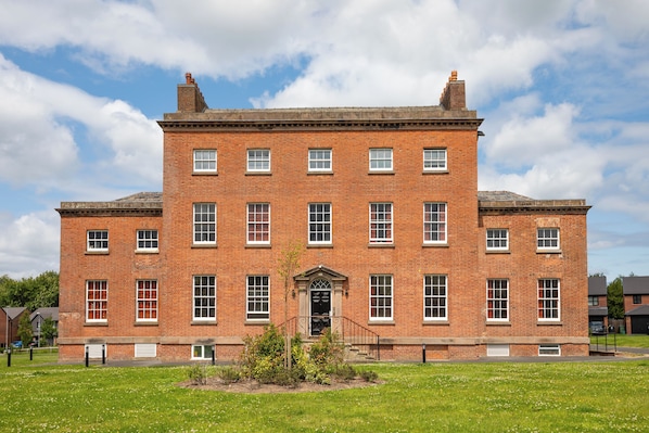 A large brick building with a symmetrical facade, multiple windows, and a central entrance.
