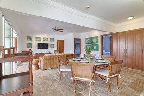 A spacious dining area with a round table, wicker furniture, and a ceiling fan. - ®{The~beach~condo} @Balcones del Atlantico (El Limón)