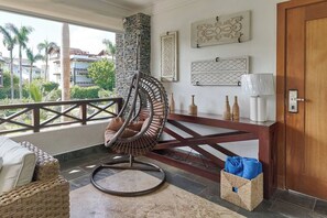 A room with a stone pillar, a wicker chair, a wooden table with bottles, and a door. - ®{The~beach~condo} @Balcones del Atlantico (El Limón)