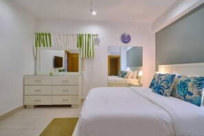 A bedroom with a bed, a dresser, a mirror, and a wall clock. - ®{Las~Olas~Beach~Condo}@JuanDolio +BeachFront+Pool (Juan Dolio)