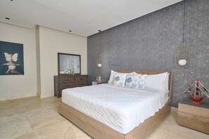 A modern bedroom with a large bed, a dresser, and a wall-mounted mirror. - ®{Costa~Sol~Views} @JuanDolio +Pool+Beachfront (Playa Juan Dolio)