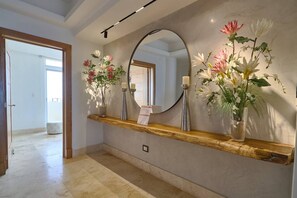 A hallway with a wooden shelf holding vases of flowers, a mirror, and a lit candle. - ®{Costa~Sol~Views} @JuanDolio +Pool+Beachfront (Playa Juan Dolio)