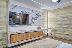 Un baño moderno con tocador de mármol, un espejo grande y un armario de madera.