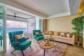 Una sala de estar moderna con un sofá, dos sillones, una mesa de centro y un ventanal con vistas al océano.