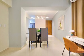 A modern dining area with a white table, two chairs, and a decorative light fixture. - ® 2BR{Ajega~Views} @Downtown SDQ +Pool+Gym (Santo Domingo)