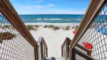 Una escalera de madera que lleva a una playa, con vista al océano.
