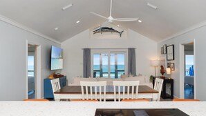 A modern kitchen with a central island, a dining area with a view, and a ceiling fan. - My Tide (Port St. Joe)