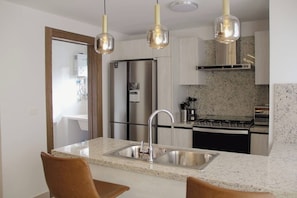 A modern kitchen with stainless steel appliances, granite countertops, and pendant lighting. - ®2BR{Santorini~Views} @Downtown SDQ +Lounge+Gym (Santo Domingo)