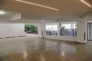 A spacious indoor area with a tiled floor, a railing, and a view of greenery outside. - ®2BR{Santorini~Views} @Downtown SDQ +Lounge+Gym (Santo Domingo)