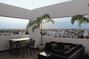 A balcony with a dining table, chairs, a sofa, and a potted plant. - ®2BR{Santorini~Views} @Downtown SDQ +Lounge+Gym (Santo Domingo)