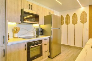 Eine moderne Küche mit Holzschränken, einem Edelstahlkühlschrank, einem Einbauofen und einer Kaffeemaschine.