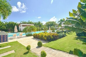 A pool area with lounge chairs, a sign indicating pool rules, and a well-maintained lawn. - ®{Coral Cliffs~Executive} @JuanDolio + Pool + Gym (Juan Dolio)