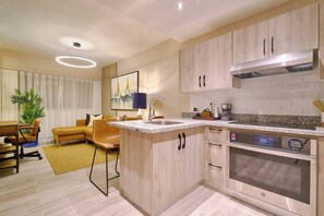 A modern kitchen with a built-in oven, a coffee maker, and a clock displaying 4:51. - ®{Coral Cliffs~Executive} @JuanDolio + Pool + Gym (Juan Dolio)