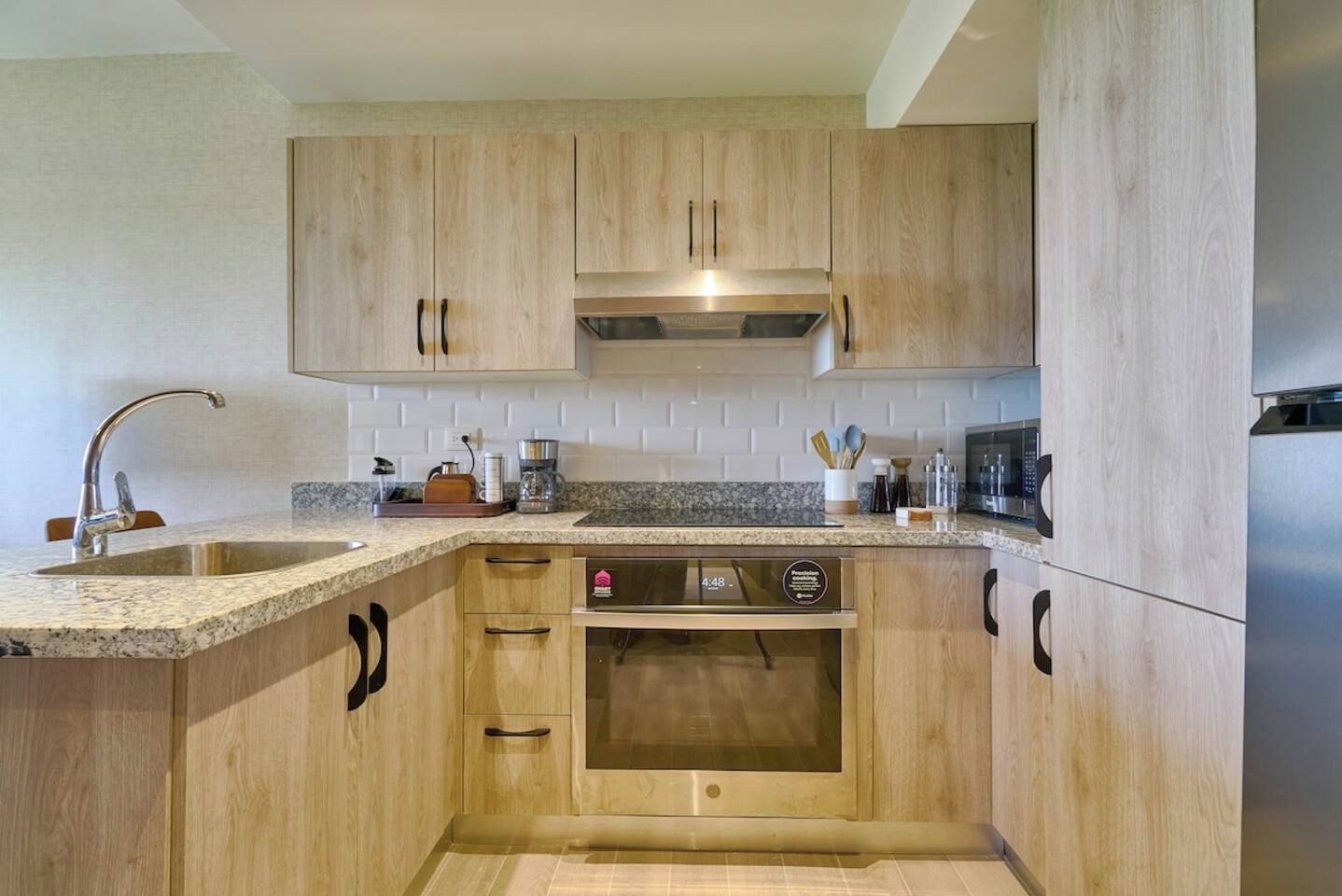 A kitchen with wooden cabinets, a stainless steel sink, and a built-in oven.
