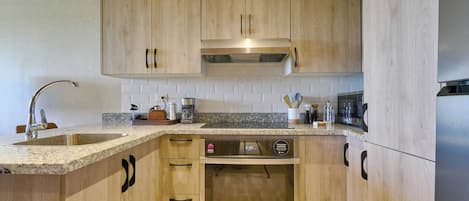 A kitchen with wooden cabinets, a stainless steel sink, and a built-in oven.