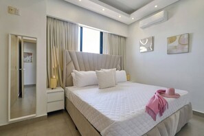 Ein modernes Schlafzimmer mit einem großen Bett, einem Nachttisch, einem Spiegel und einem Fenster mit Vorhängen.