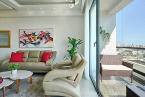 Ein stilvolles Wohnzimmer mit einer Couch, roten Kissen, einem Couchtisch und einem großen Fenster.