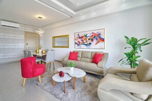 Un salon moderne comprenant un canapé, des fauteuils, une table basse et un coin repas.