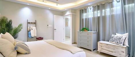 Une chambre à coucher moderne avec un lit, une commode, un ventilateur de plafond et une porte de salle de bain.