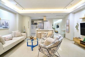 A modern living room with a sofa, chairs, a coffee table, and a TV. - ®{Marbella~LUX~Essence} Beachfront+Pool+11thFloor (Playa Juan Dolio)