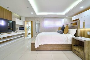 Une chambre moderne avec un grand lit, un téléviseur intégré et une coiffeuse avec un miroir.