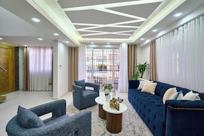 A modern living room with a blue sofa, grey armchairs, and a coffee table. - ®{San~Angel~View} @DowntownSD +BBQ+Close-to-Mall (Santo Domingo)