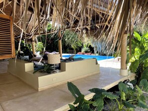 A poolside area with a thatched roof, seating, and tropical plants. - 4BR{Beach~by~Melo} @LosNomadas +2Min Beach+Pool (Las Terrenas)