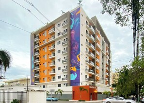 A multi-story building with balconies, a mural on the side, and a sign for 'Melcon IV'. - ®{City~Art~Place}@DowntownSD+Pool+GymClose toOcean (Santo Domingo)