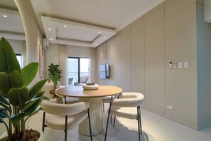 Un espace repas moderne avec une table ronde, des chaises rembourrées et une plante en pot.