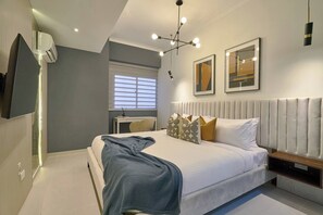Une chambre à coucher moderne avec un grand lit, un bureau et un téléviseur.