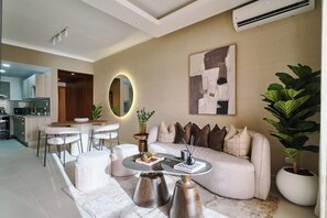 A modern living room with a sofa, coffee table, and a dining area with chairs. - ®{City~Art~Place}@DowntownSD+Pool+GymClose toOcean (Santo Domingo)