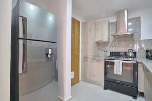 A modern kitchen with stainless steel appliances, wooden cabinets, and granite countertops. - ®{City~Art~Place}@DowntownSD+Pool+GymClose toOcean (Santo Domingo)