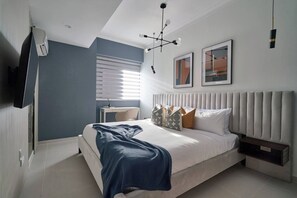 A bedroom with a bed, bedside table, and a mounted TV. - ®{City~Art~Place}@DowntownSD+Pool+GymClose toOcean (Santo Domingo)