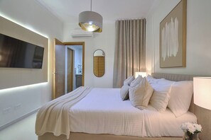 Een moderne slaapkamer met een groot bed, een flatscreen televisie, een spiegel en een schilderij aan de muur.