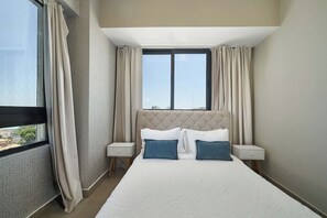 Una camera d'albergo con un letto grande, due comodini e una finestra con tende.