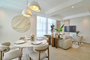 A modern dining area with a round table, chairs, and pendant lighting. - ®(The~LUX~Natural~Art) @DowntownSD +Pool+Gym+2BR (Santo Domingo)