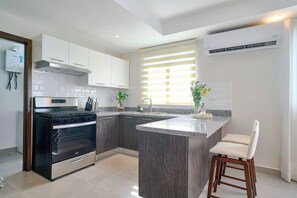 A modern kitchen with a central island, stainless steel appliances, and a window with blinds. - ®(The~LUX~Natural~Art) @DowntownSD +Pool+Gym+2BR (Santo Domingo)
