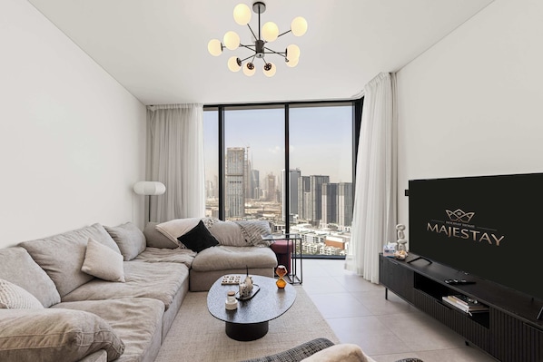 A modern living room with a sofa, coffee table, and a TV. - Cozy 1BR Retreat,  Prime Location (Dubai)